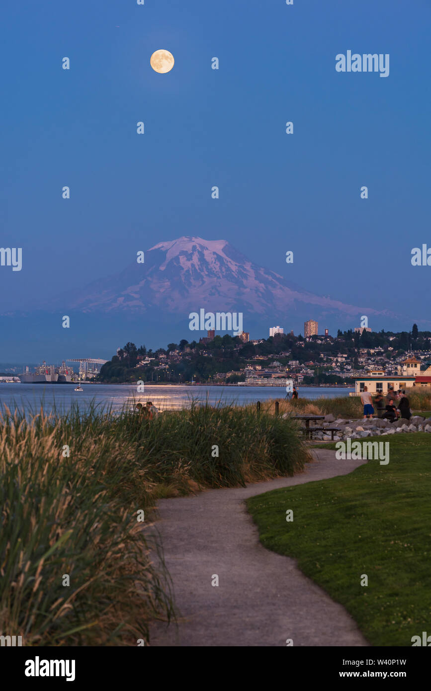 Mt Rainier Hovers Over Downtown Tacoma and Commencement Bay as Seen from Point Ruston with people walking Stock Photo