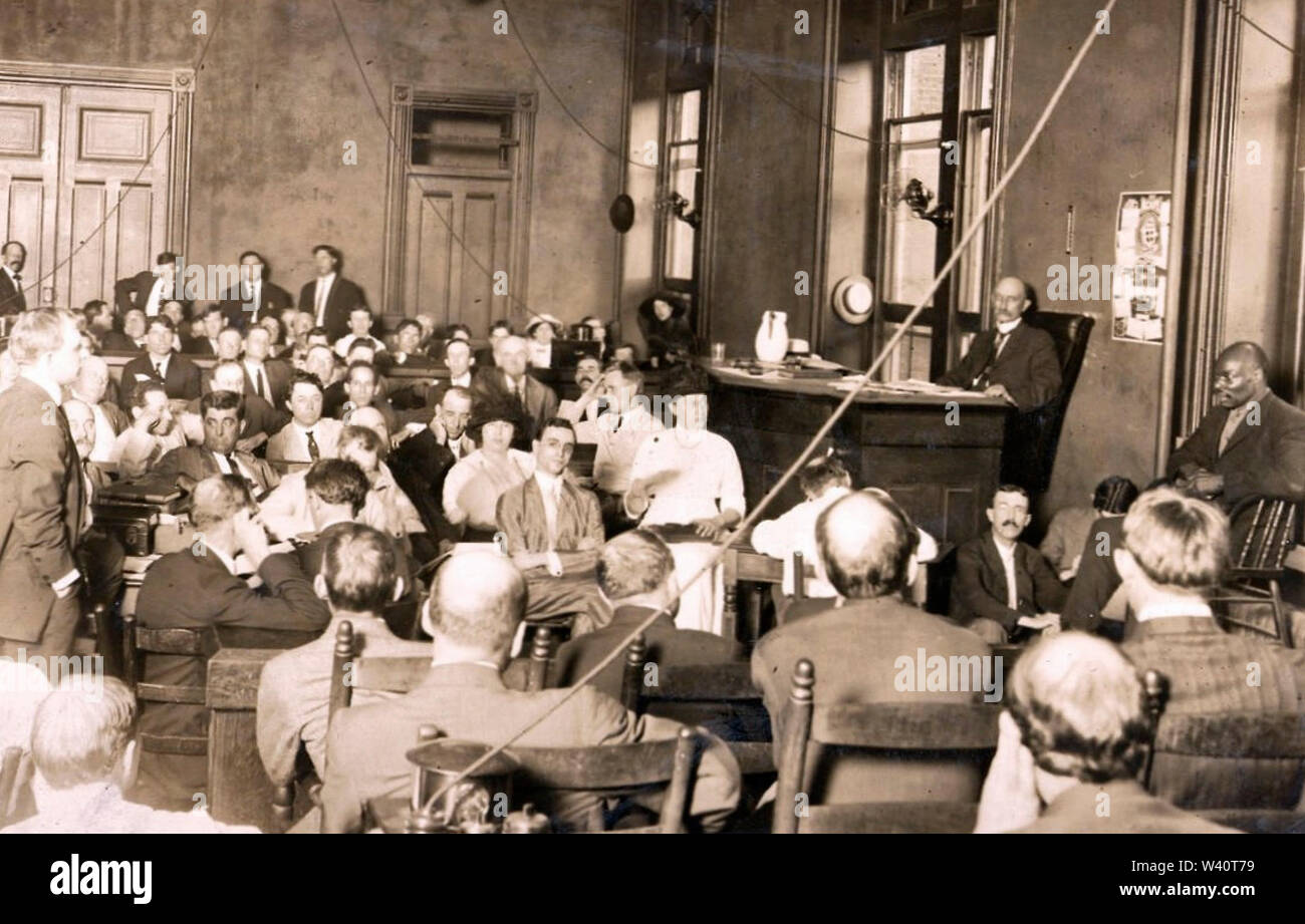Photo of the trial of Leo Frank, shot on July 28, 1913. Prosecutor Hugh Dorsey, standing at left, is examining witness Newt Lee, at right. Leo Frank who is seated in the centre, staring at the camera. The jury are in the foreground with their backs to the camera. Also in the picture are Lucille Frank, Leo Frank's wife, and Mrs Ray Frank, his mother. 28 July 1913 Stock Photo
