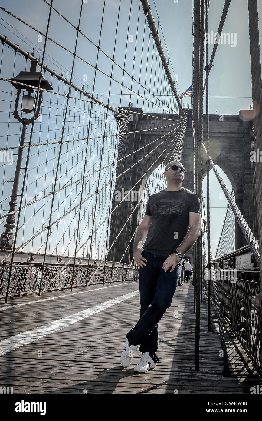 Young Man Posing on the Brooklyn Bridge on sunny day Stock Photo