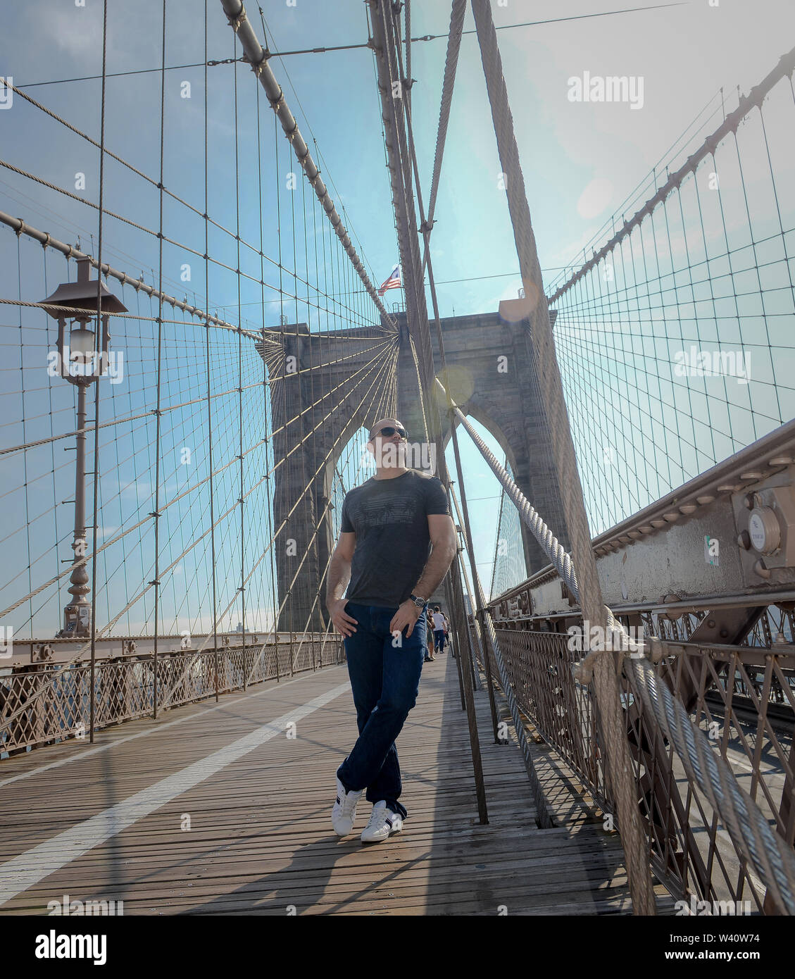 Young Man Posing on the Brooklyn Bridge on sunny day Stock Photo