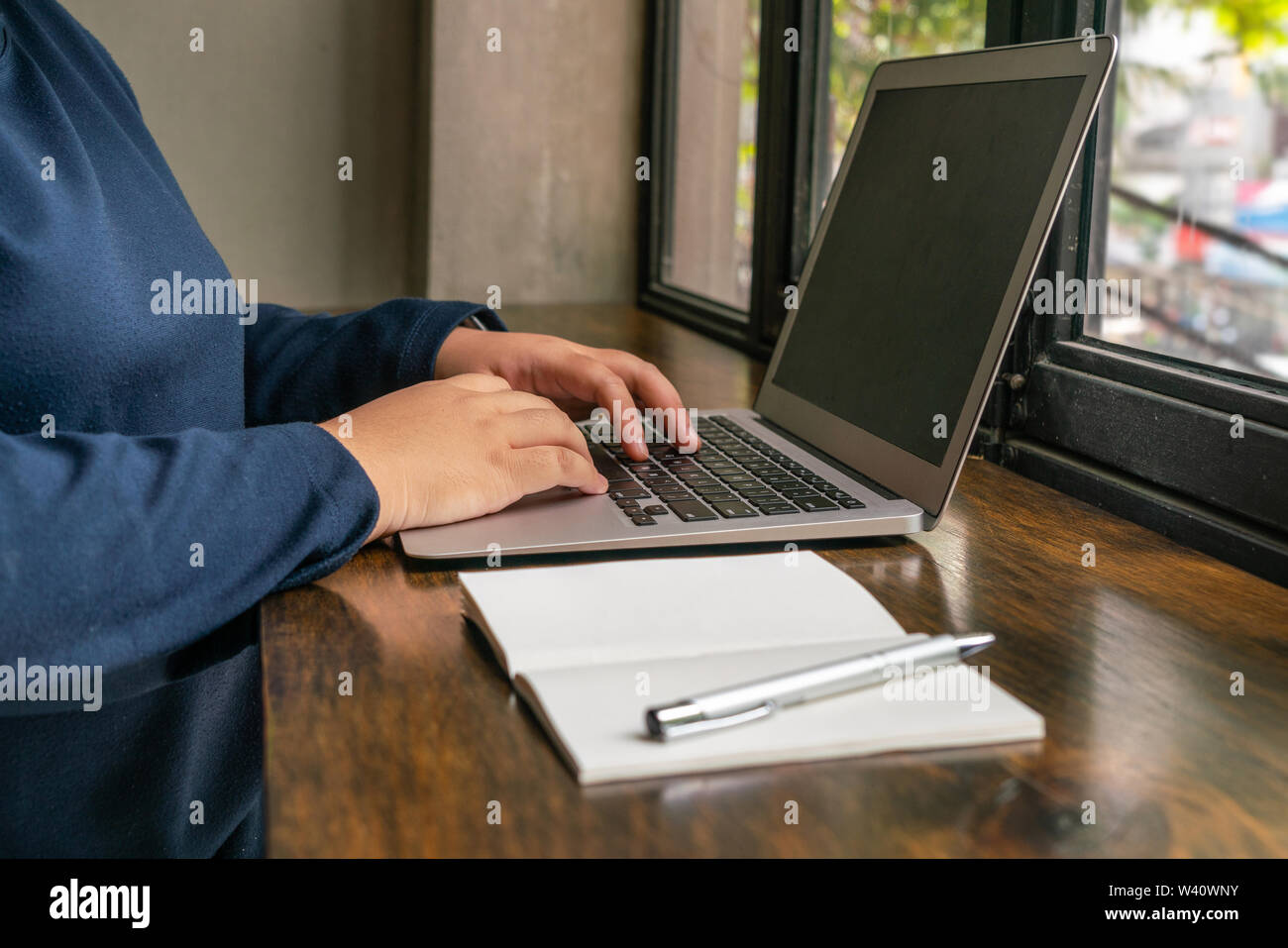 Woman hands using laptop next to notebook Stock Photo