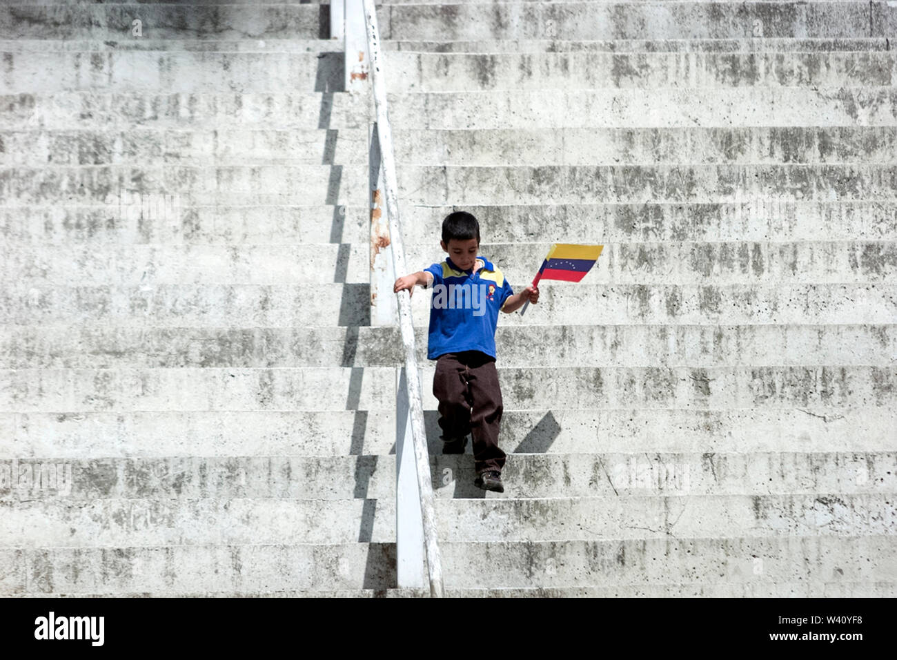 A boy holding a Venezuelan flag goes down stairs in Caracas, Venezuela Stock Photo