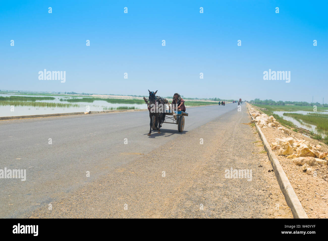 Rahim yar khan, Punjab,Pakistan-June 23,2019: a villager sitting on a horse cart on a high way,a man is driving a horse cart on a road. Stock Photo