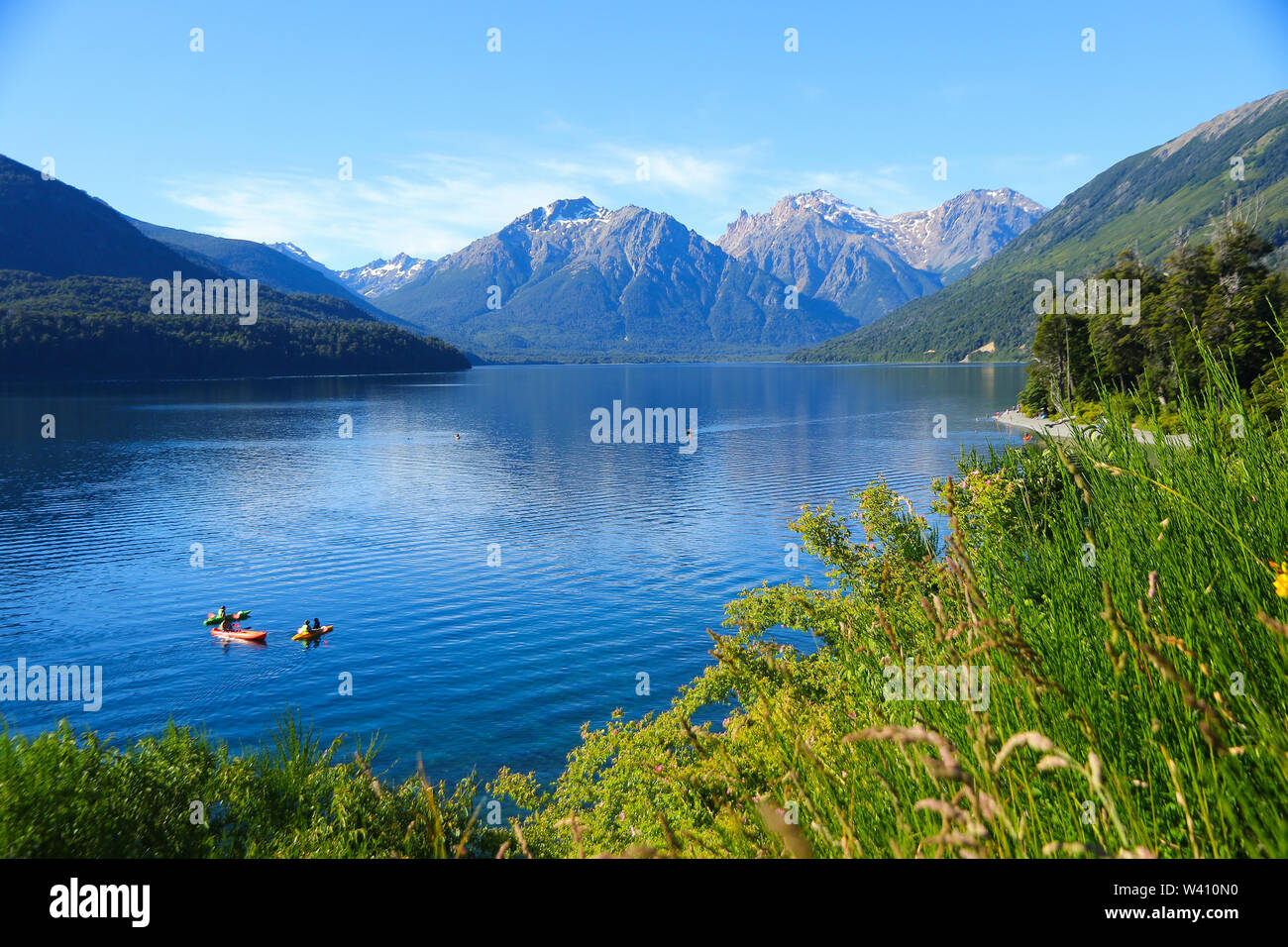 Tourists enjoying the blue waters of Mascardi lake in a canoe, south of San Carlos de Bariloche in Patagonia, Argentina, under a snow-covered mountain Stock Photo