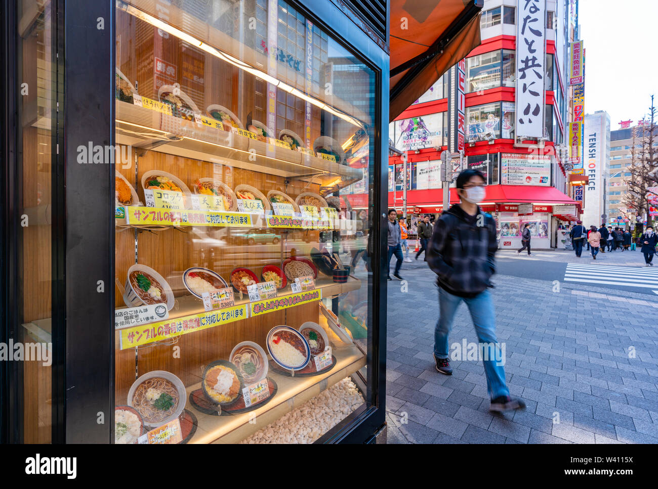 Man walking past a japanese in Tokyo Stock Photo