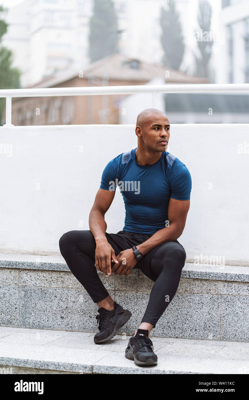 Handsome fit african fitness man resting after workout outdoors, sitting  Stock Photo - Alamy