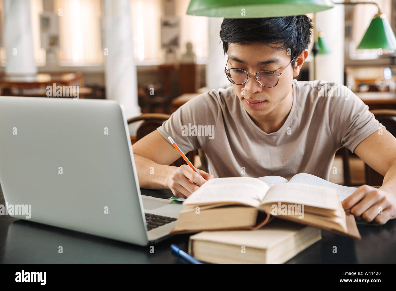Smiling asian teenager student studying at the library Stock Photo - Alamy