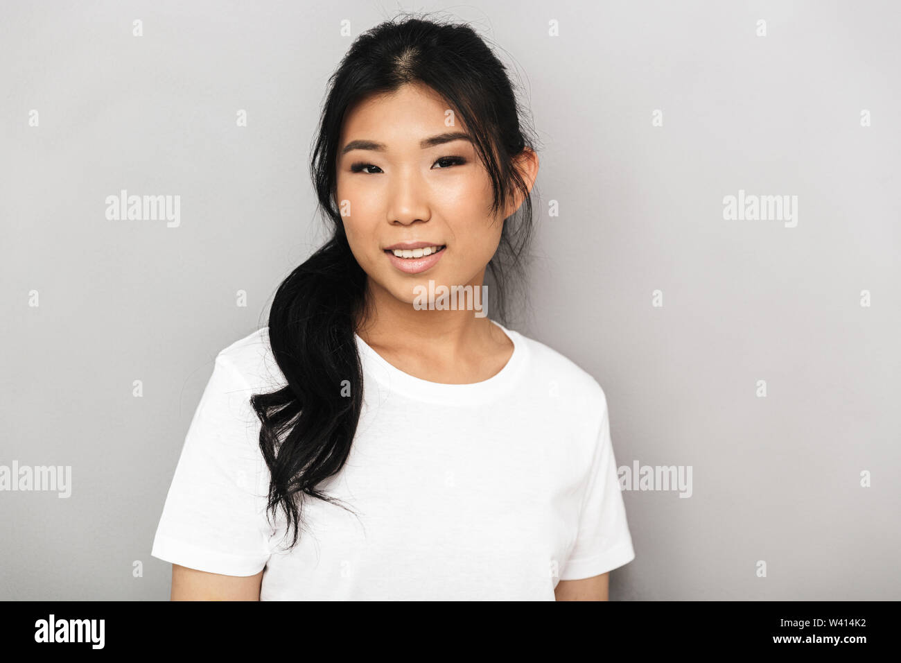 Image of asian beautiful young woman posing isolated over grey wall ...