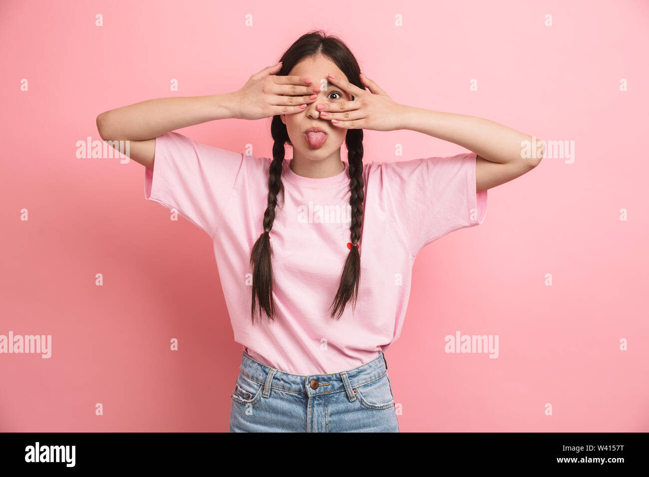 Image of sweet cheerful girl with two braids smiling and covering her ...