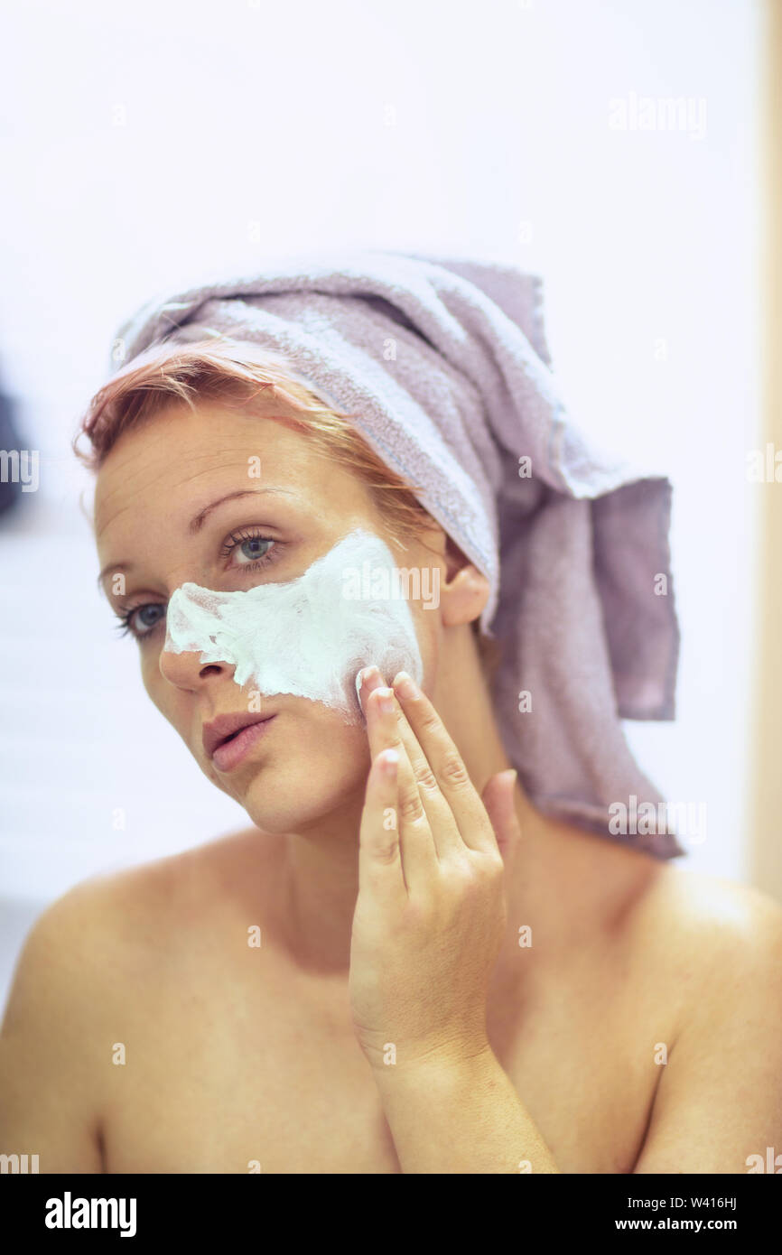 Young woman applying facial mask. Beauty treatments. Stock Photo