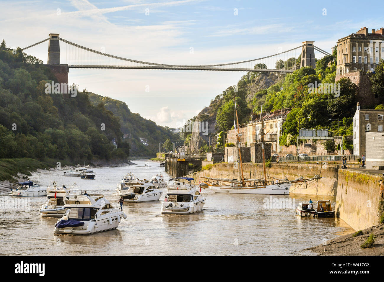 Boats make their way through the Avon Gorge and underneath Clifton Suspension Bridge as they head to Bristol harbour for the Bristol Harbour Festival, where hundreds of vessels from tall ships to dinghies will gather in the city centre floating harbour. Stock Photo