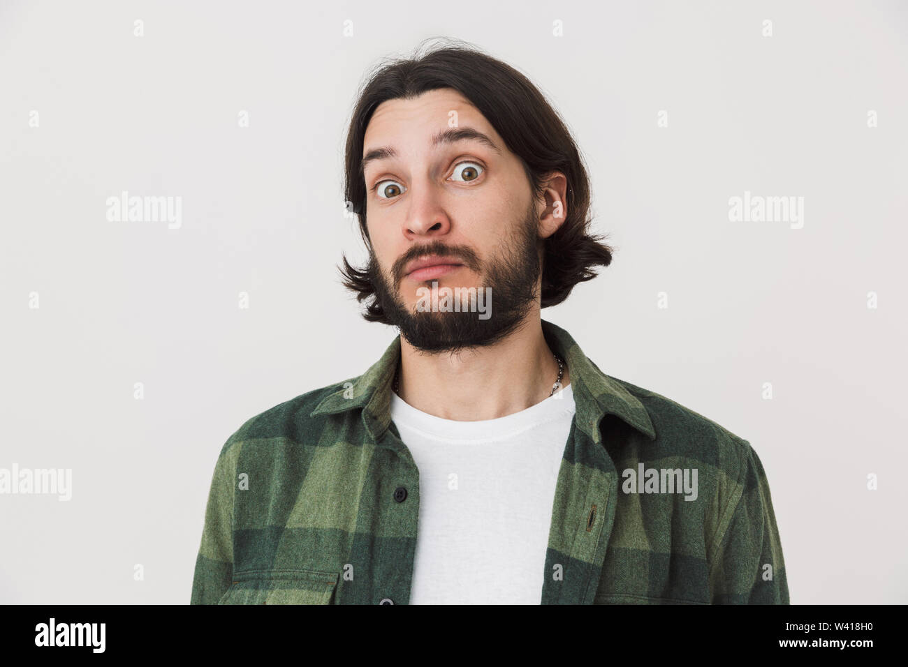 Portrait of a confused surprised young bearded brunette man wearing plaid shirt standing isolated over white background Stock Photo