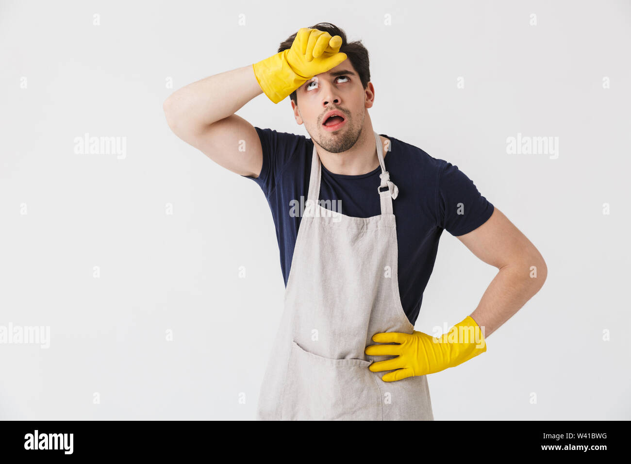 Photo of tired young man wearing yellow rubber gloves for hands