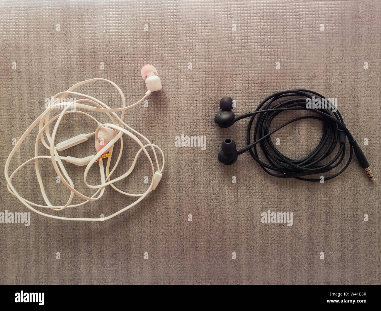 Two pairs of black and white wired headphones, for music listening