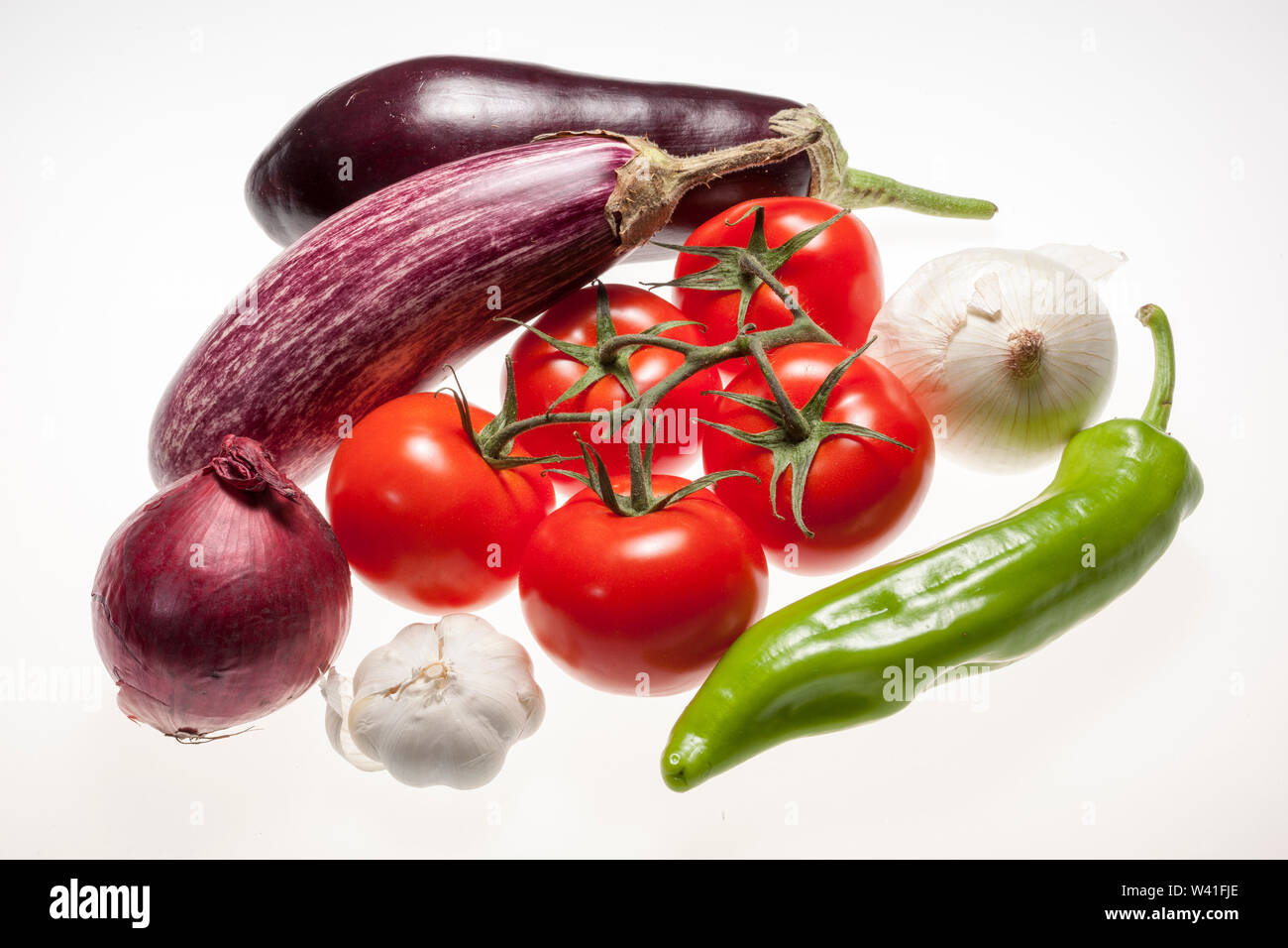 Fresh eggplants, tomatos, green pepper, onion and garlic over white background Stock Photo