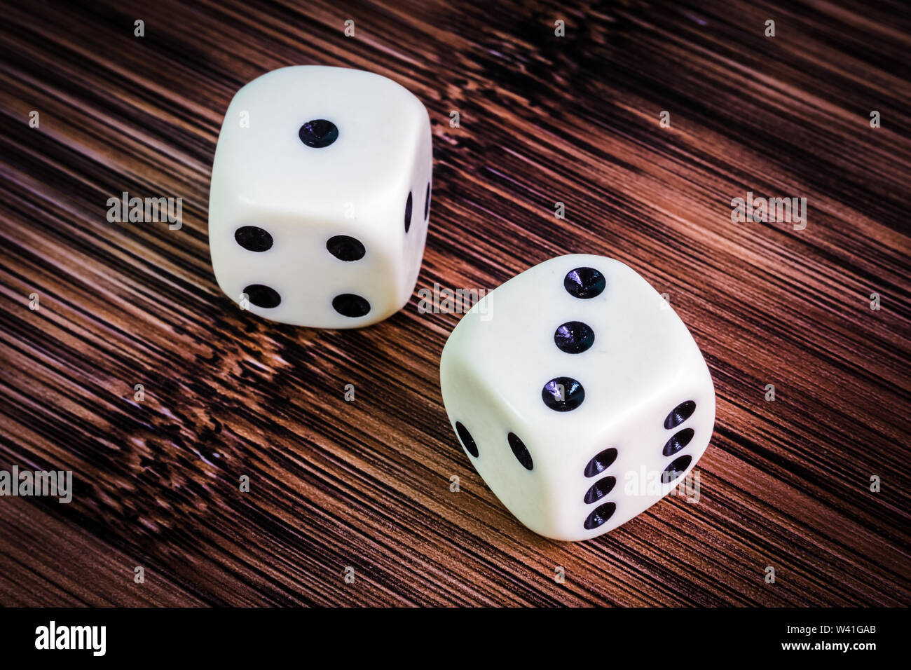 White dice isolated on bamboo grain textured background Stock Photo
