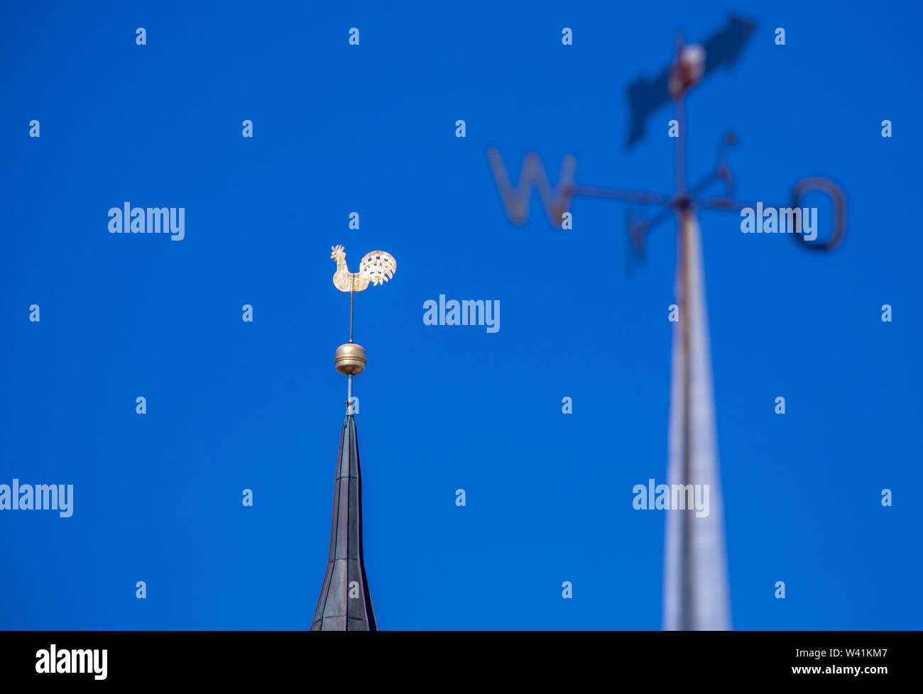 Schaprode, Germany. 11th July, 2019. The golden weathercock turns on the church spire behind a weather vane with the cardinal points. The island of Rügen is a holiday destination for hundreds of thousands of tourists every summer. Credit: Jens Büttner/dpa-Zentralbild/ZB/dpa/Alamy Live News Stock Photo