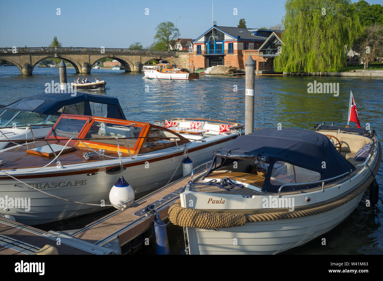 Pleasure boats moored on the river thames at Henley-on-Thames with the Henley Royal Regatta Headquarters and Henley Bridge behind. Stock Photo