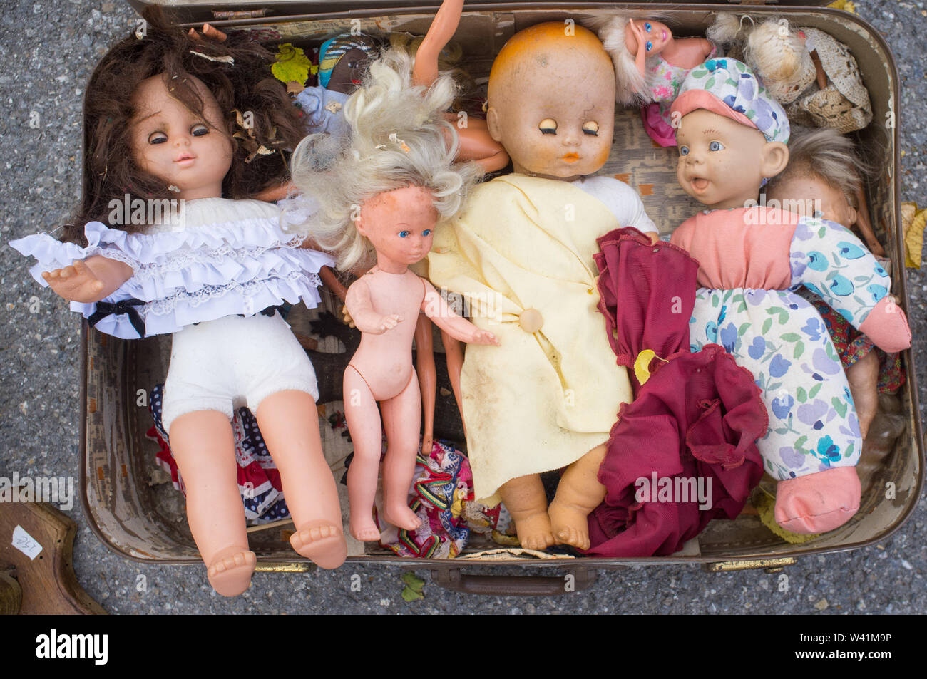 A suitcase displaying antique dolls for sale at a rural French market. Stock Photo