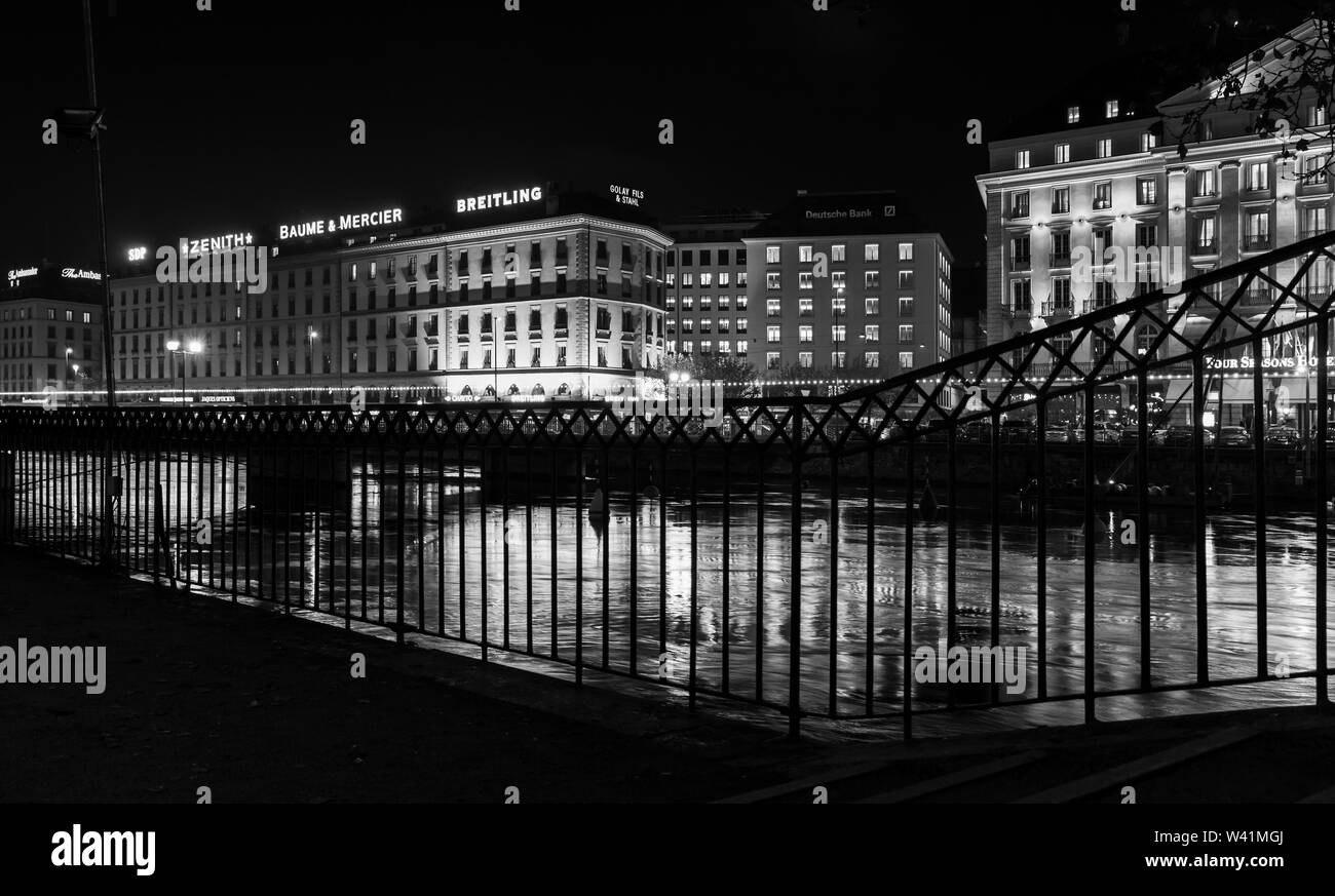 Geneva, Switzerland - November 24, 2016: Night black and white cityscape with illuminated facades and reflections in Rhone river water. Geneva city ce Stock Photo