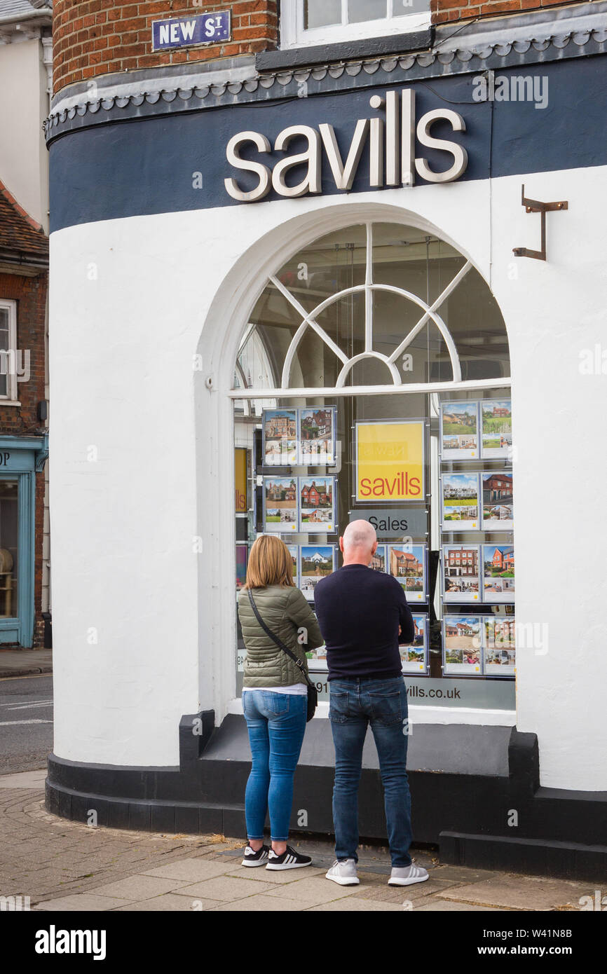 A couple look in the window of Savills estate agents in Henley-on-Thames Stock Photo