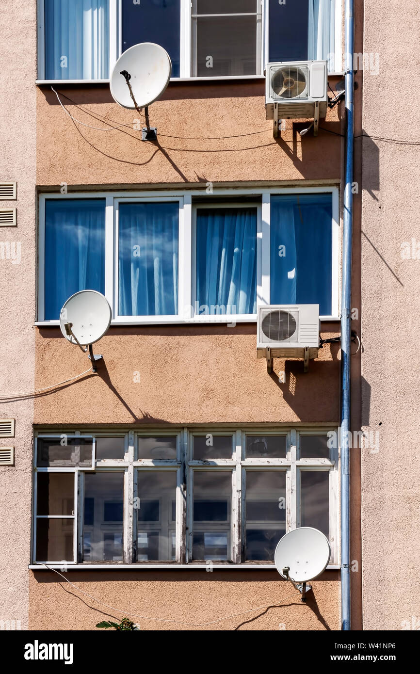 The facade of an apartment building with air conditioning and satellite