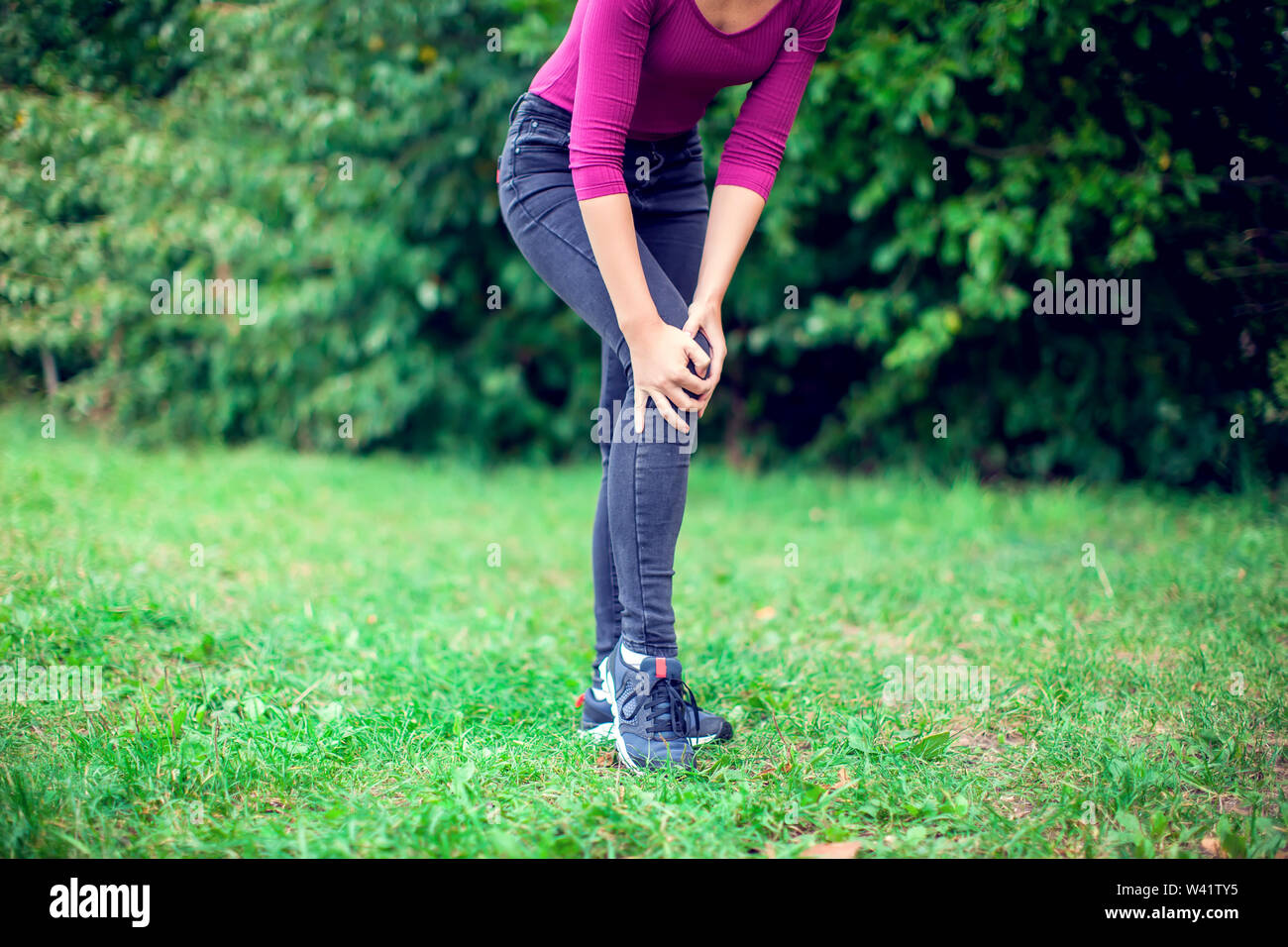 Healthcare, medicine and people concept. Woman suffering from pain in knee outdoor Stock Photo
