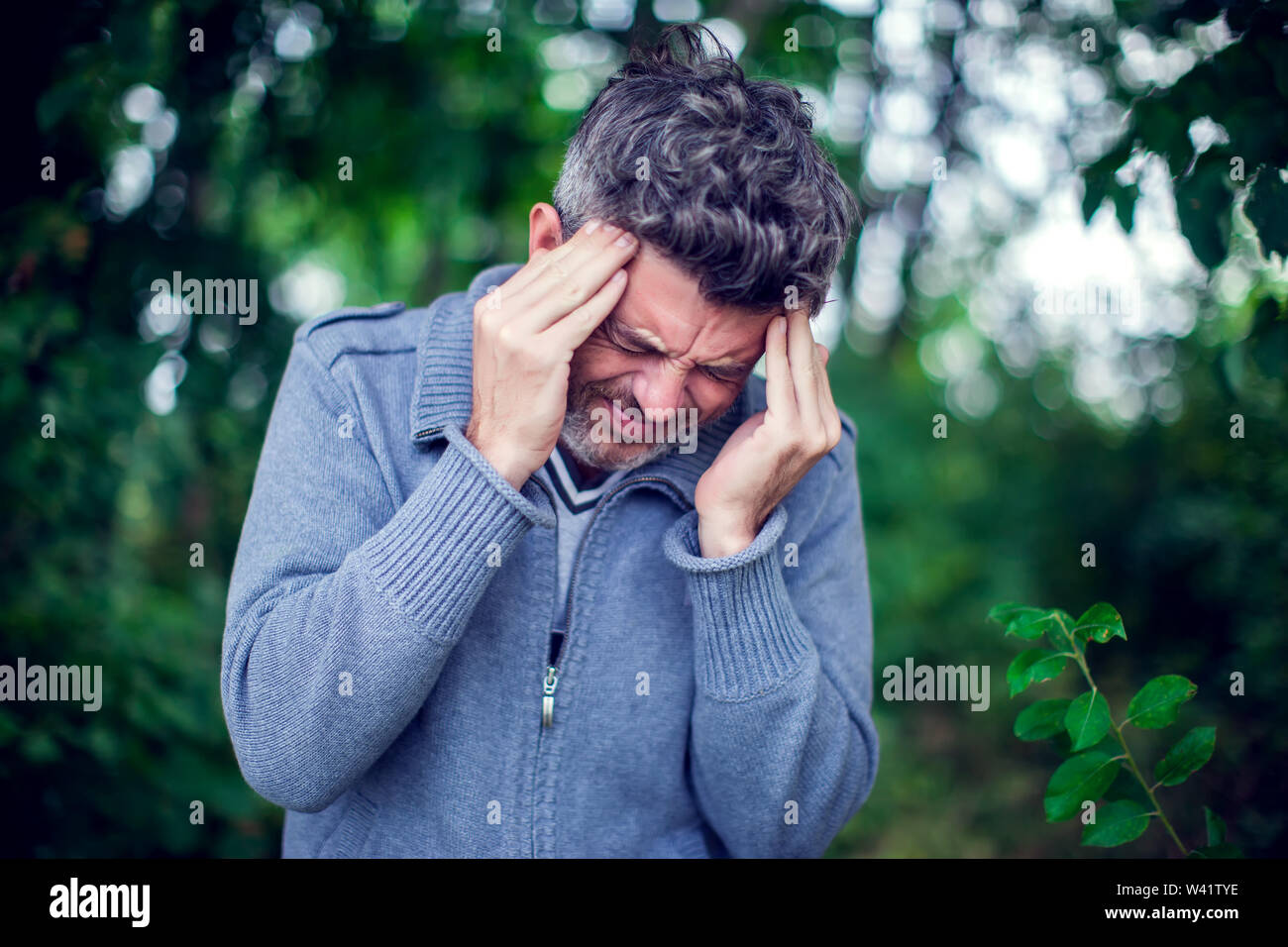 Portrait of a sick man having a migraine outdoor. Healthcare, medicine and people concept Stock Photo