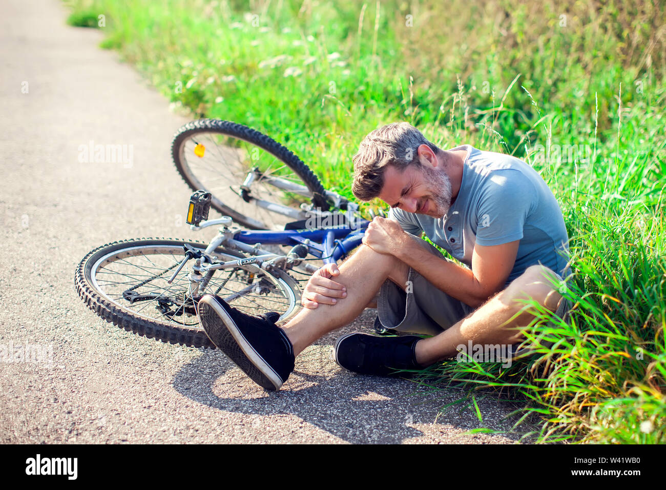 Man with dark hair with pain in knee joints after biking on bicycle