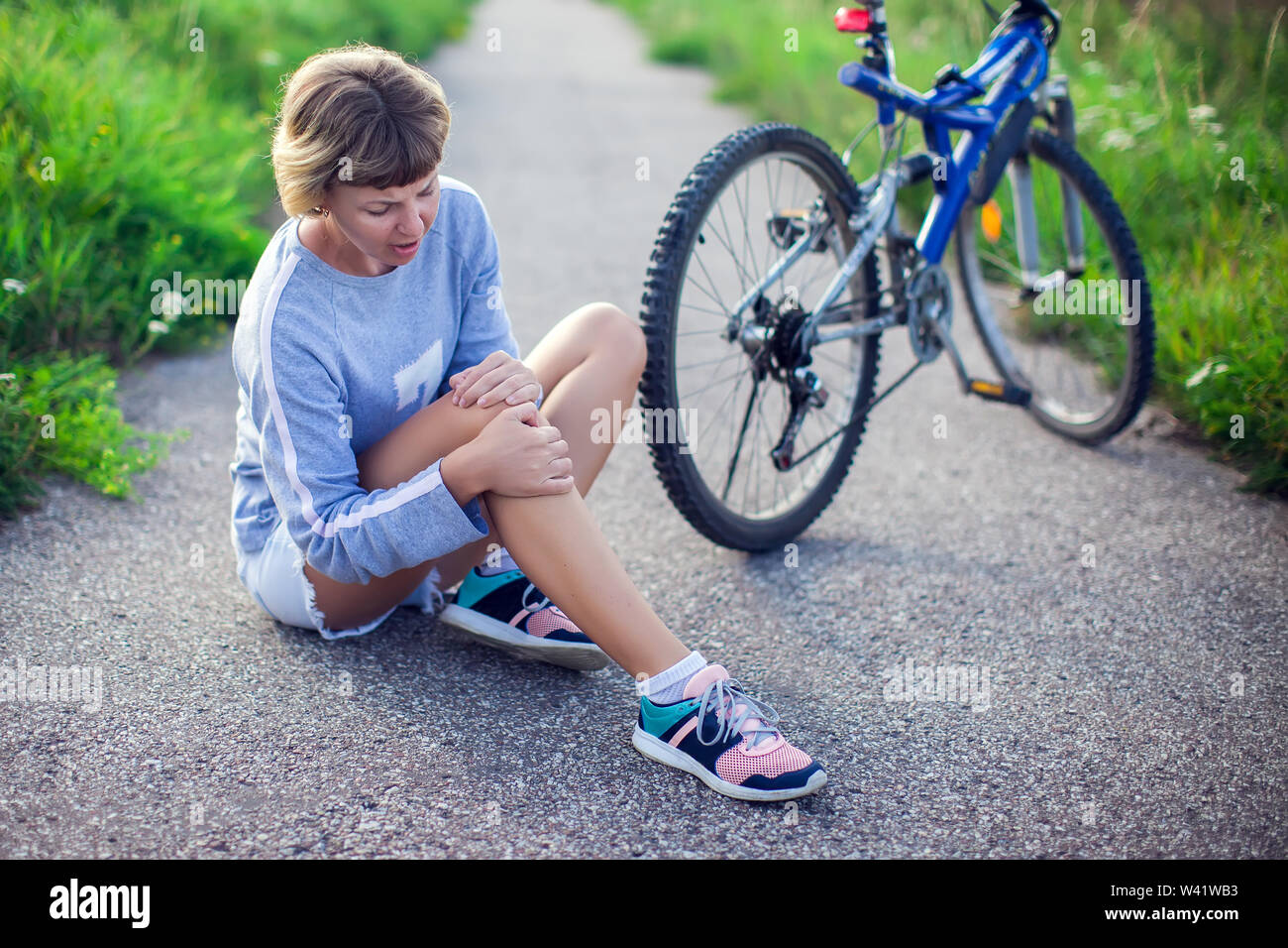 Woman with short hair with pain in knee joints after biking on bicycle