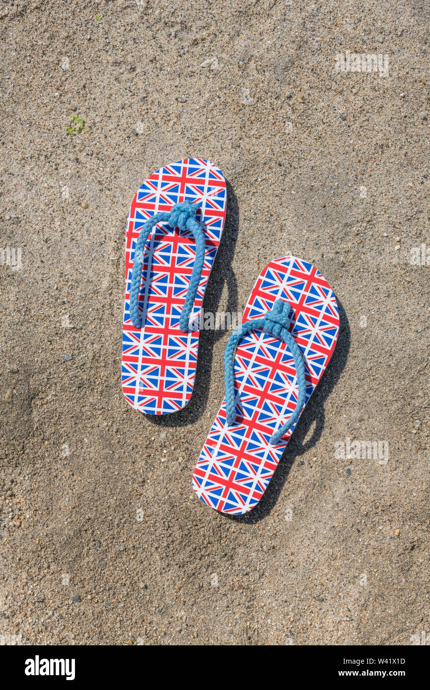 GB flag / Union Jack flipflops on sandy beach for 2021 UK staycation