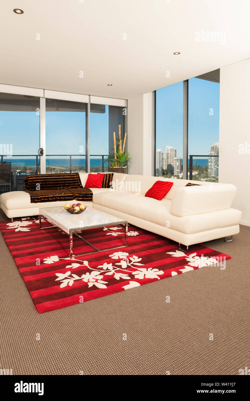 Image of a spacious living room with a white sofa, red carpet and big