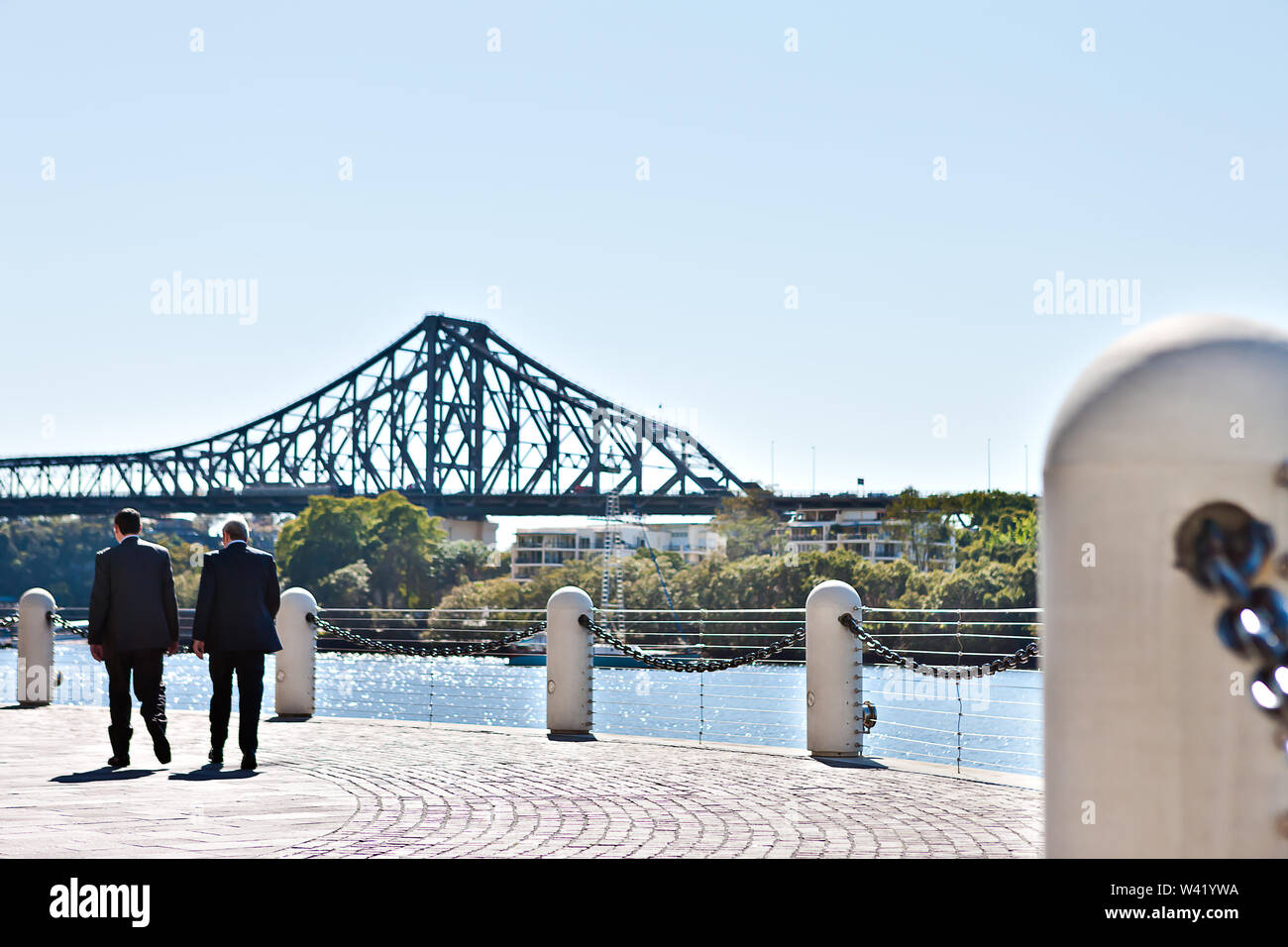 businessmen walking on the riverside stone tile street with a concrete