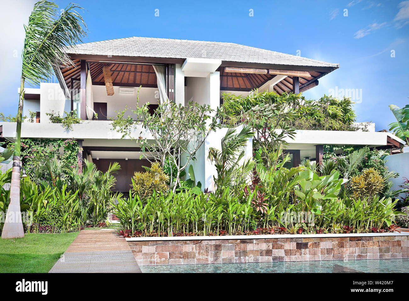 Modern house with a garden and the pool shining in the sunlight under blue  sky Stock Photo - Alamy