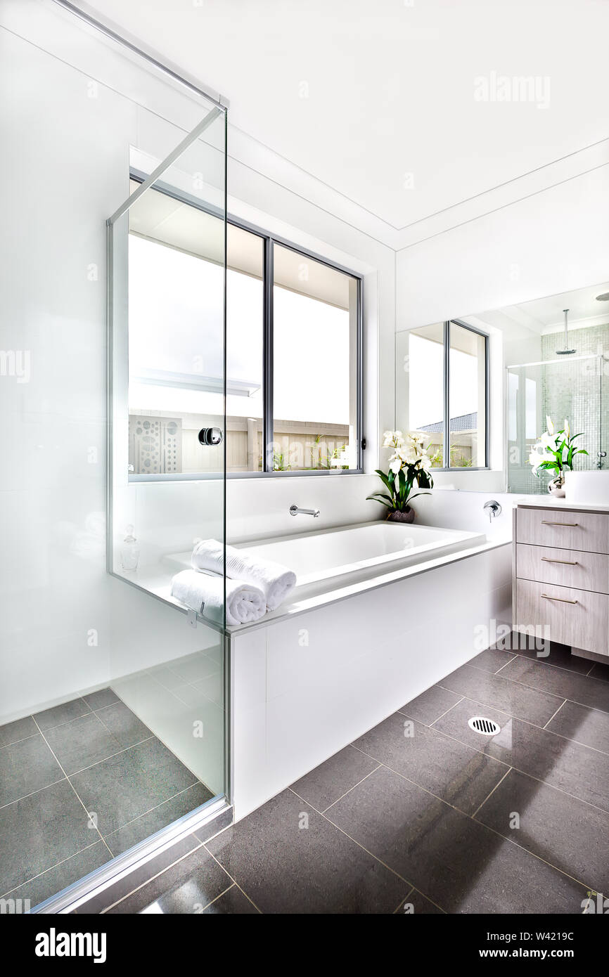 Luxury bathroom floor is made of shiny tiles. The bathing area is