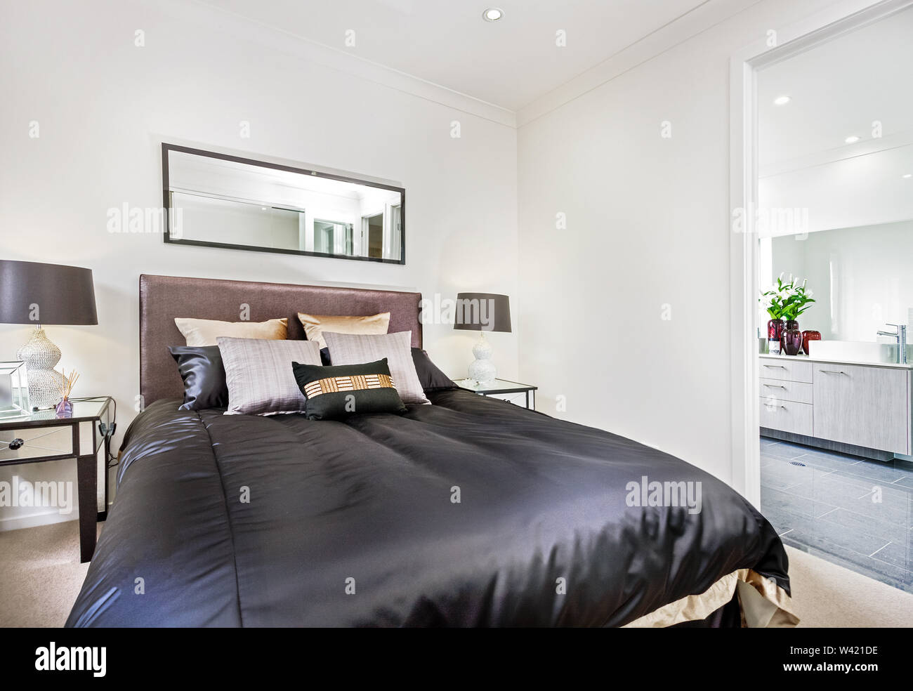 Cozy doublebed with cushions and sidetables with table lamps in the