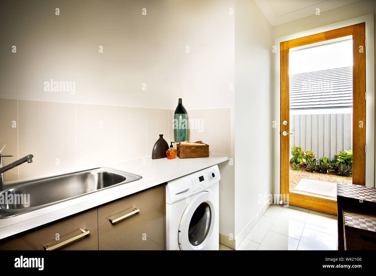 Modern White Color Washing Machine Under The Countertop With A Faucet And A Silver Sink The Washing Area Has White Tiles And Wall Is A Gray Color Th Stock Photo Alamy