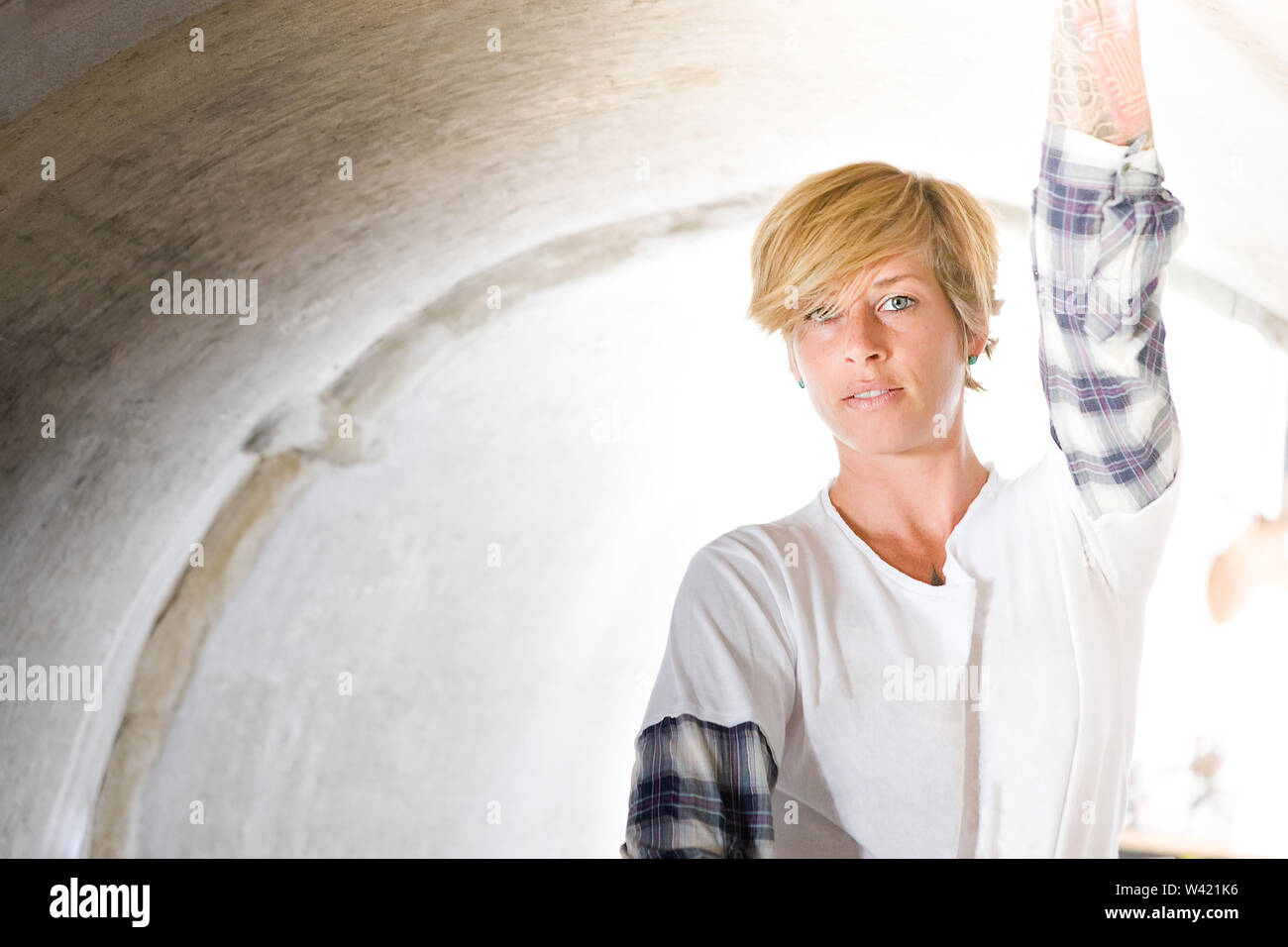 Short haired girl touching the inside of a concrete drain  pipe Stock Photo