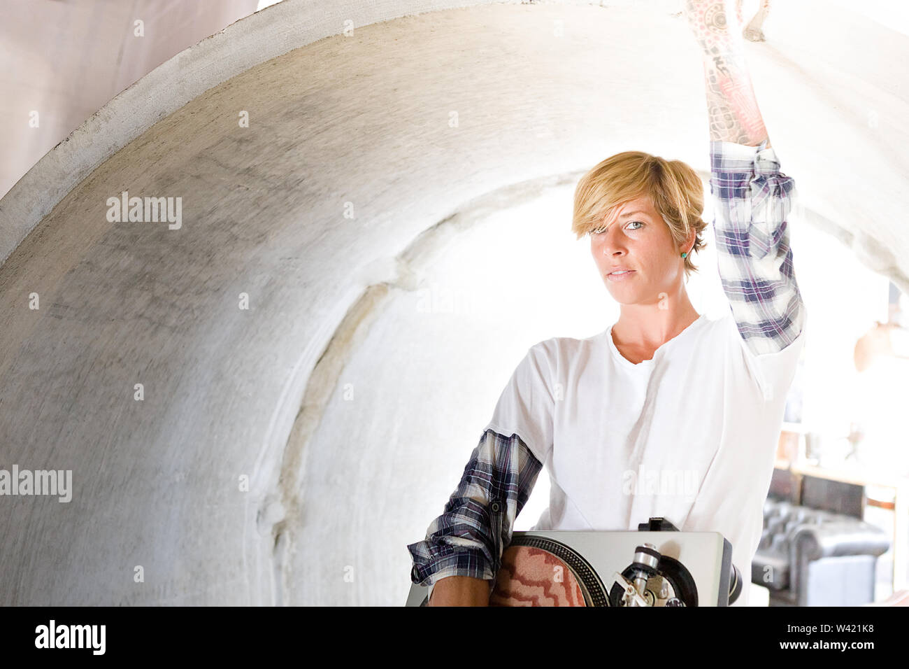 Gold haired girl touching the inside of a pipe with a serious look and holds a gramophone Stock Photo