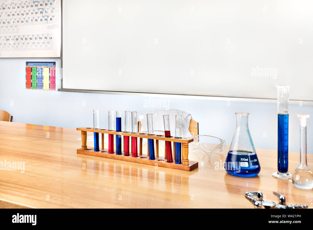 Laboratory items on the wooden table, including science beaker and