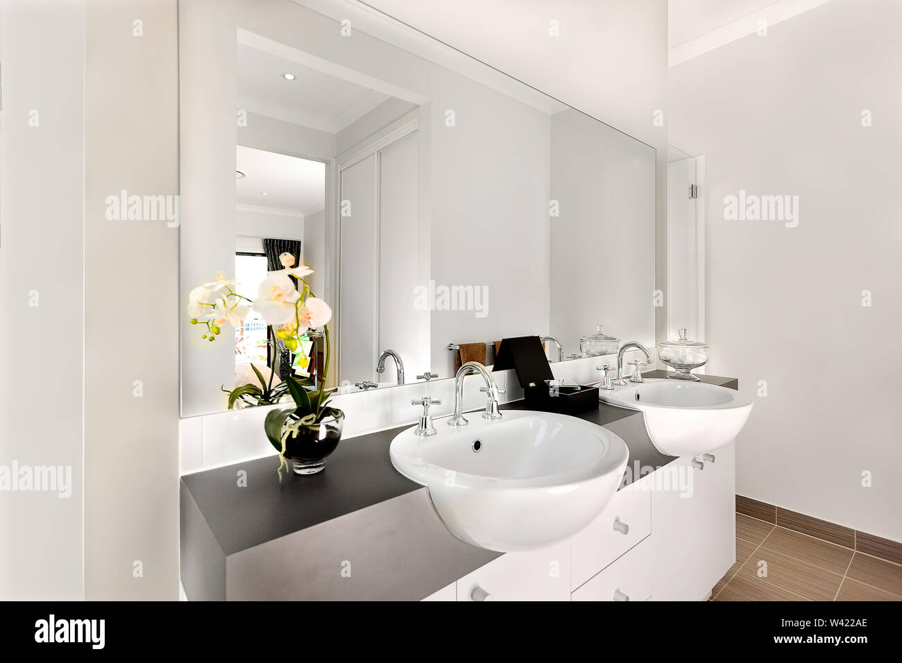 Luxurious washroom included two shiny white washstand made of ceramic, there are silver and curved faucet fixed to sink. The taps can give warm water. Stock Photo