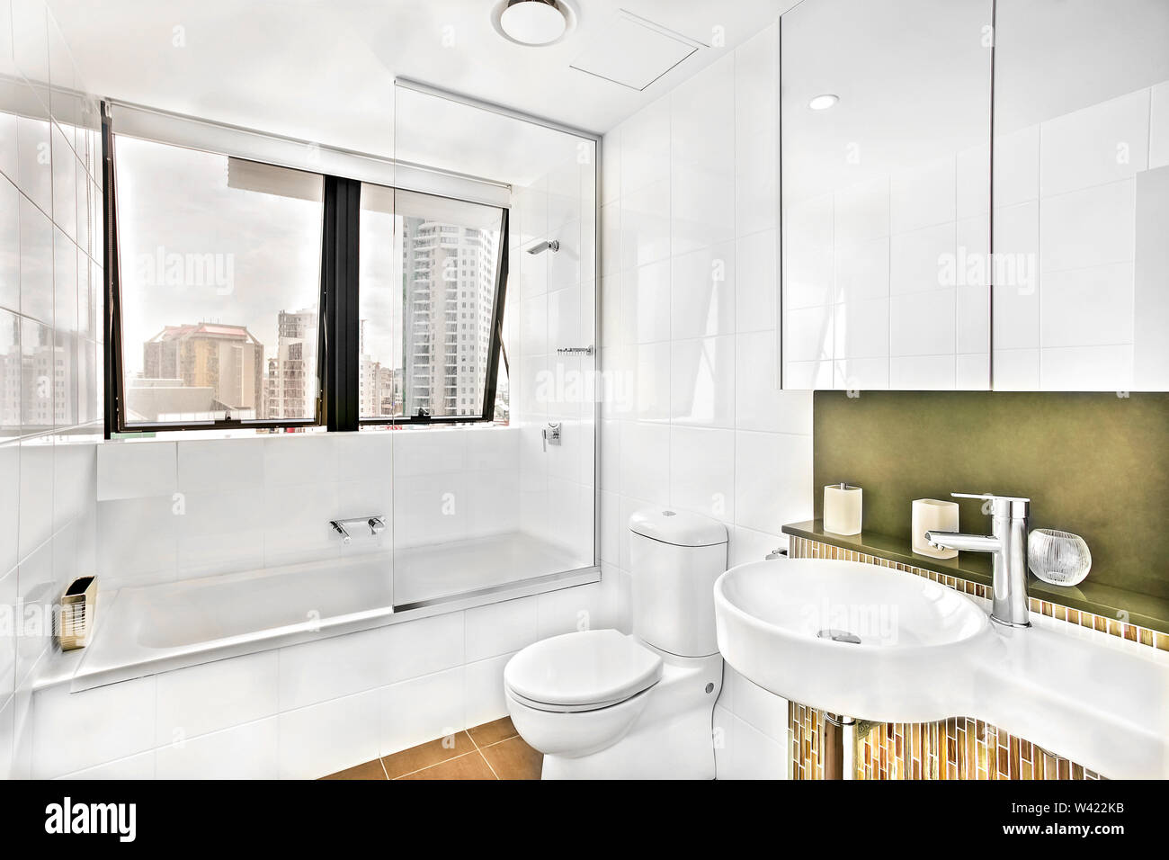 Washroom near glass windows with tiles, wash area and toilet decorated