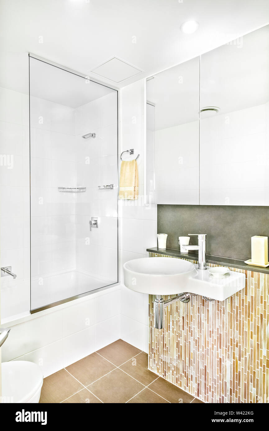 Modern wash room near mirror with tiles, wash area and the toilet