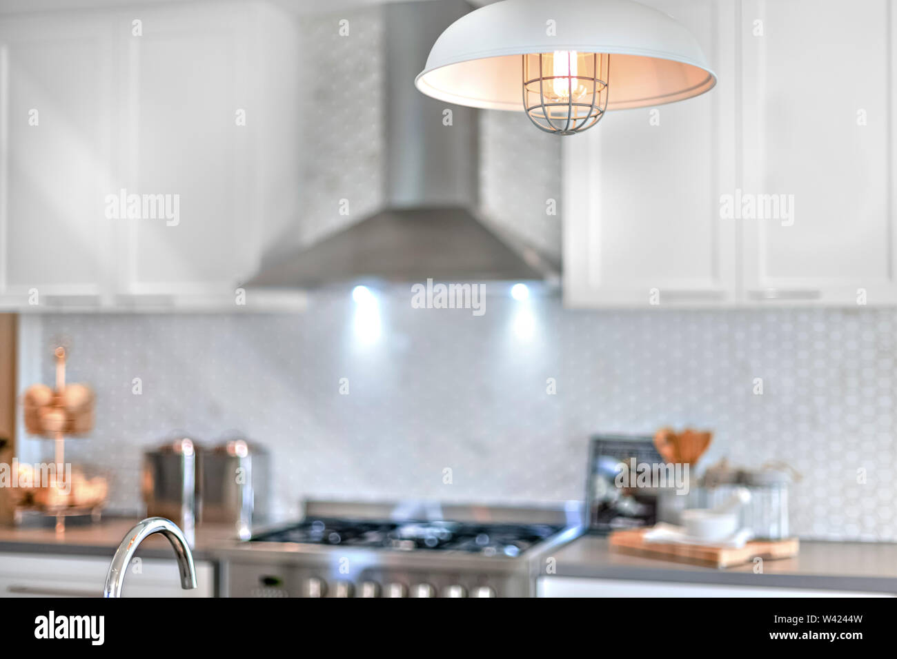 Hanging lamp illuminating with the blurred kitchen background in a modern house or hotel Stock Photo