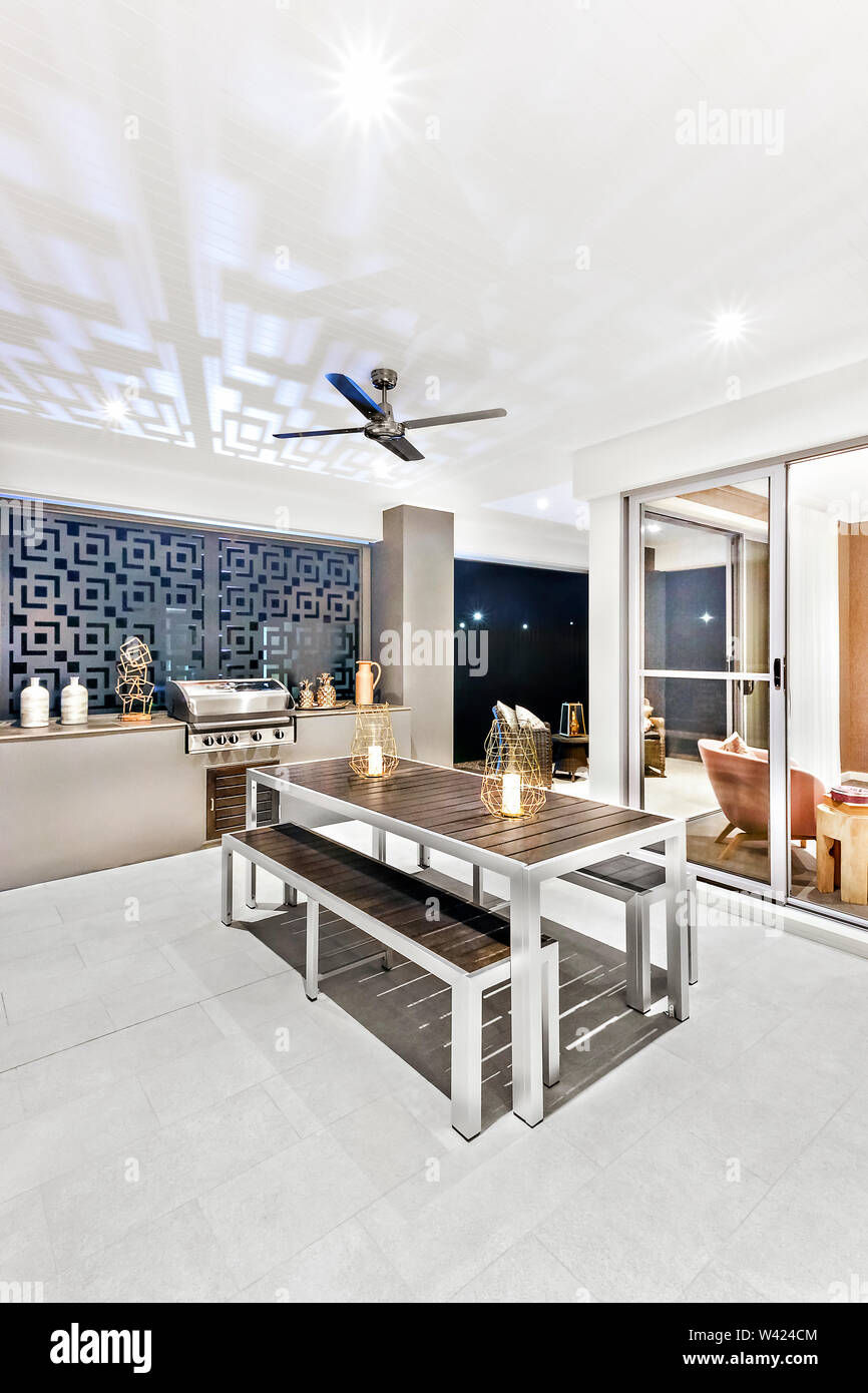 Room with a dining area and tile floor, there is black wooden table with a  bench beside the glass door entrance, fan can see on ceiling, luxury home i  Stock Photo -, image size:866x1390