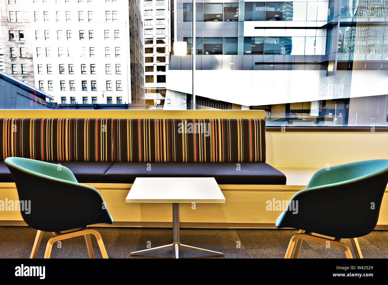 Modern Dining Room With Two Chairs And One Square Shape Table Next To The Long Cushion Front Of Glass Window Showing Outside Buildings Stock Photo Alamy