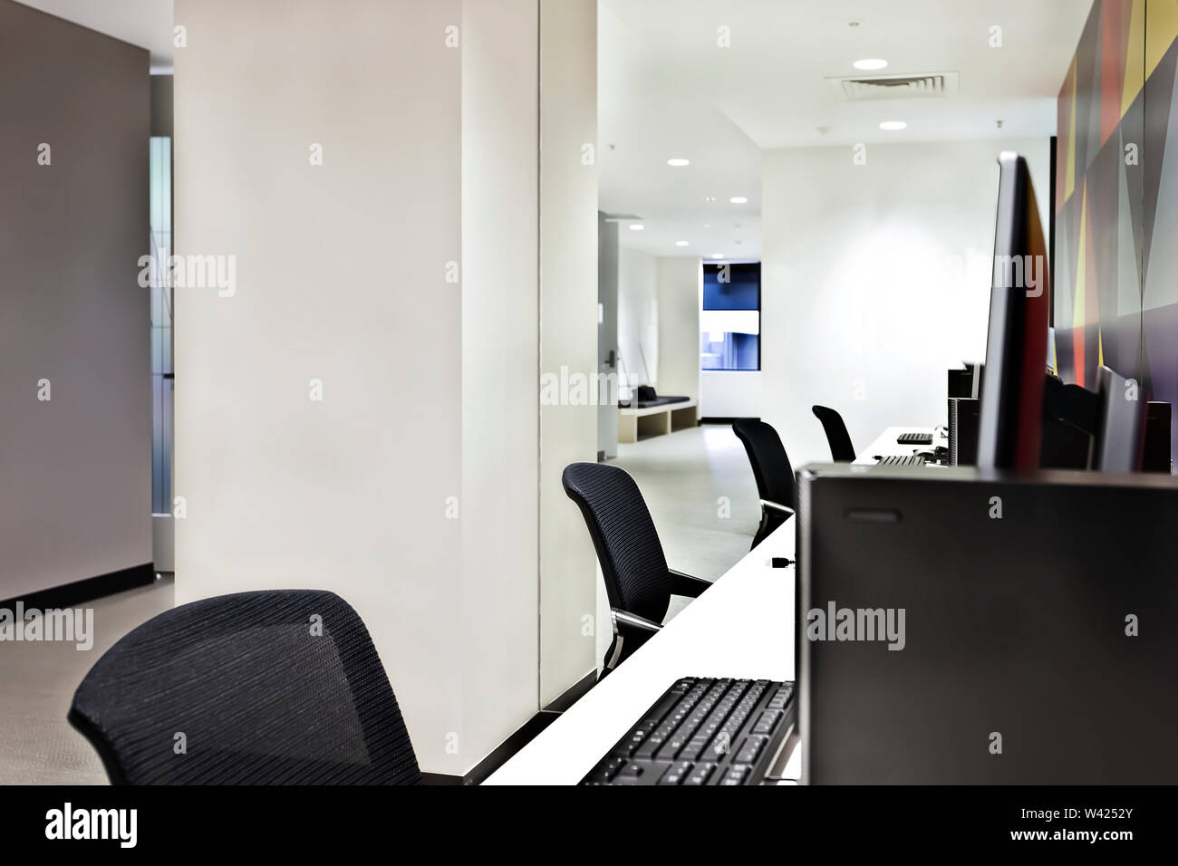 Work place with computers, monitors and chairs with a room inside illuminated using lights Stock Photo