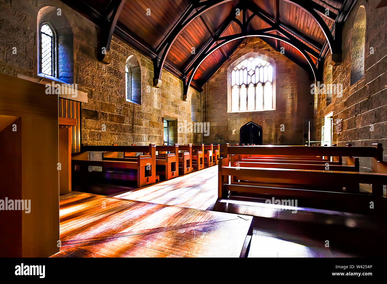 Inside of a church with wooden benches and floor under the old looking