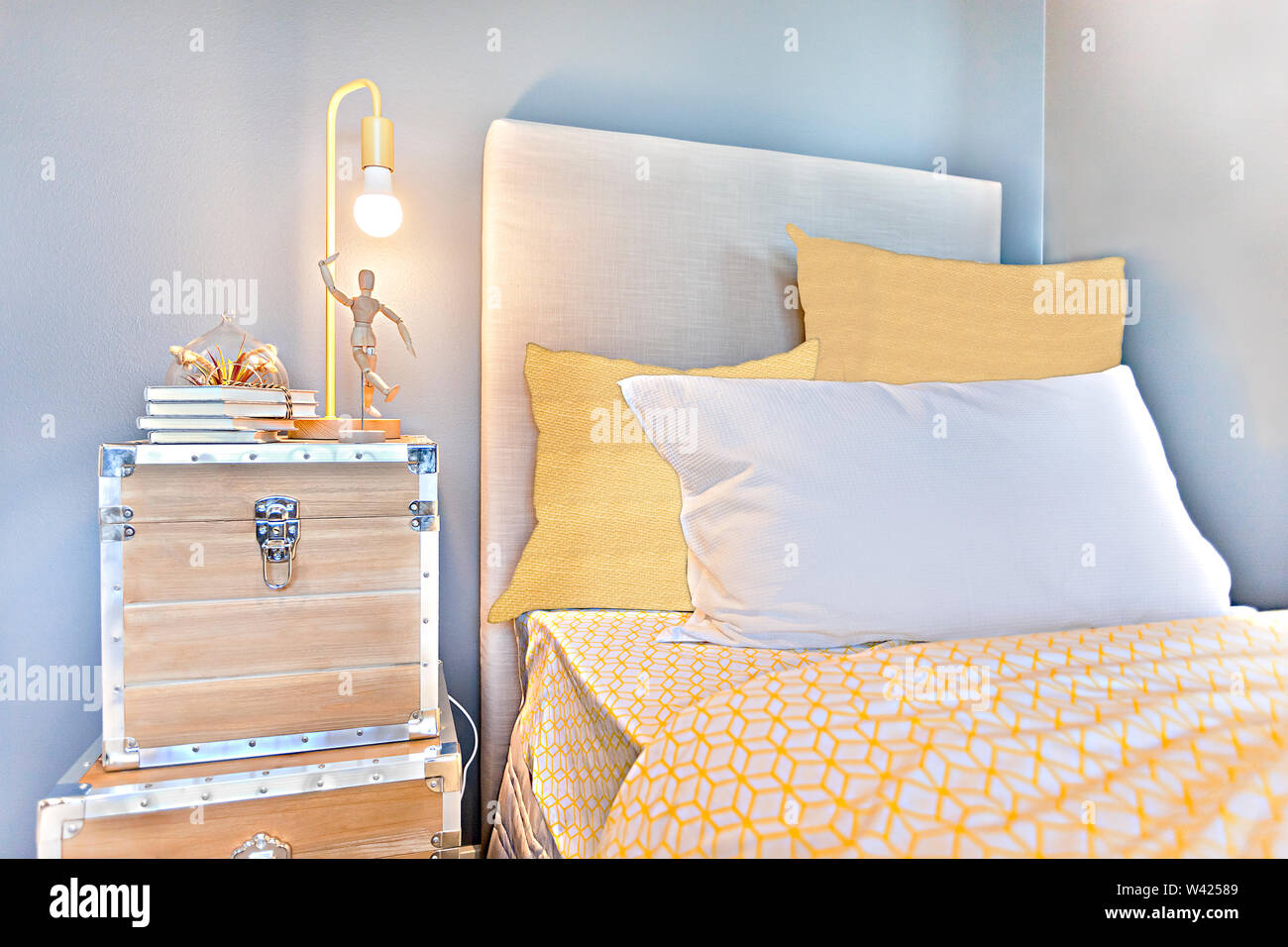 Bedroom with yellow blankets and pillows beside wooden suitcases near