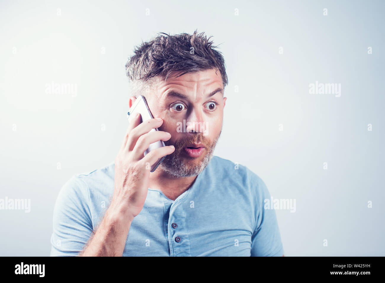Handsome young man surprised using mobile phone Stock Photo